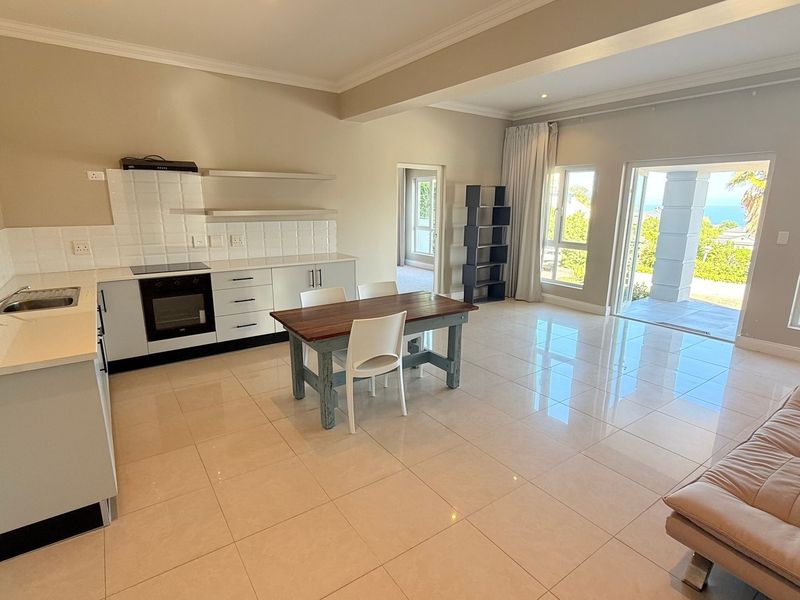 Spacious open-plan kitchen and living area featuring modern cabinetry, tiled floors, and direct access to a patio with scenic views.