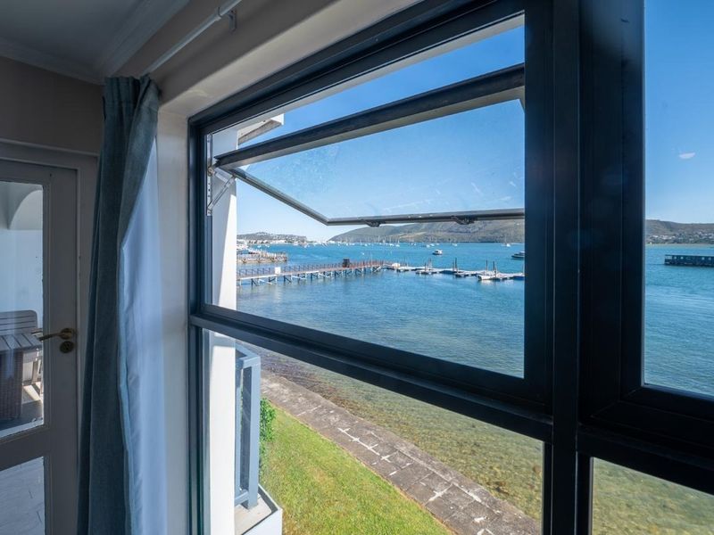 A clear view of the marina and bay through a modern casement window, showcasing the waterfront location.