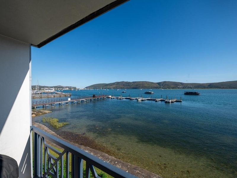A scenic view of the lagoon and marina, captured from a private balcony with a metal railing.