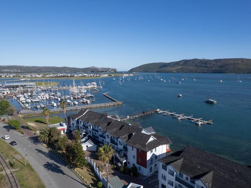 An aerial view of the apartment complex situated along the waterfront, featuring proximity to the marina, jetty, and scenic estuary views.