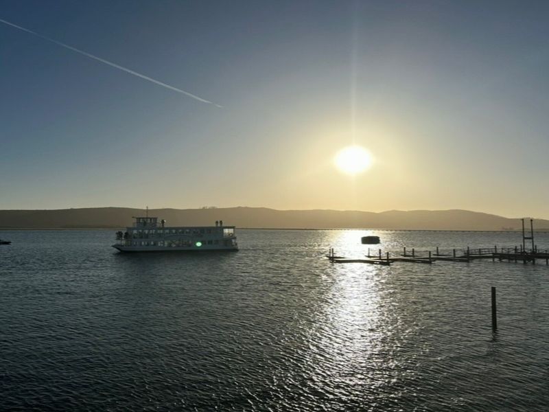 A scenic view of the lagoon at sunset, featuring a wooden jetty and a boat in the distance.