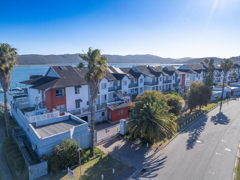 Aerial view of a multi-story apartment complex featuring pitched roofs, balconies, and secure gated access, situated near the waterfront.