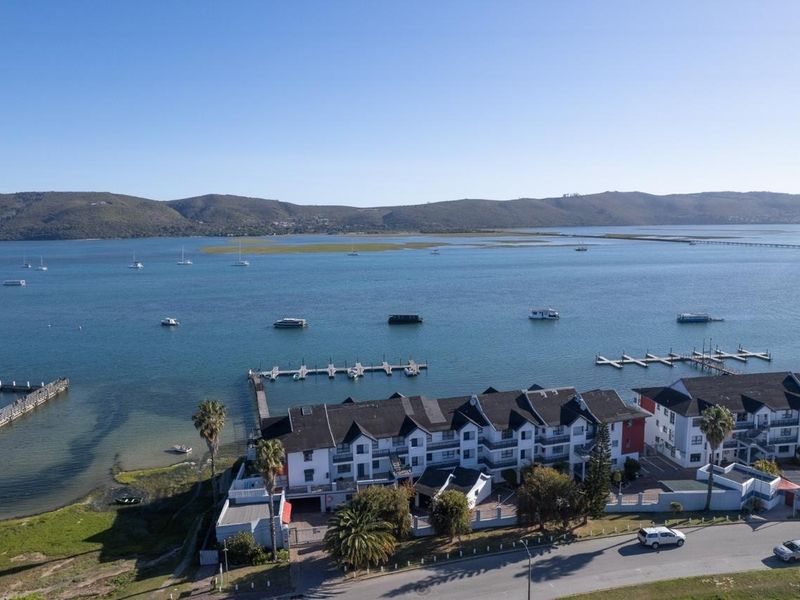 Aerial view of a waterfront apartment complex featuring private jetty access, landscaped grounds, and direct views over the lagoon.