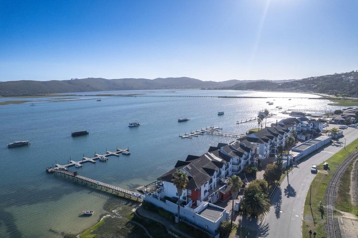 Aerial view of a waterfront apartment complex featuring private jetties, direct lagoon access, and proximity to local road and rail infrastructure.