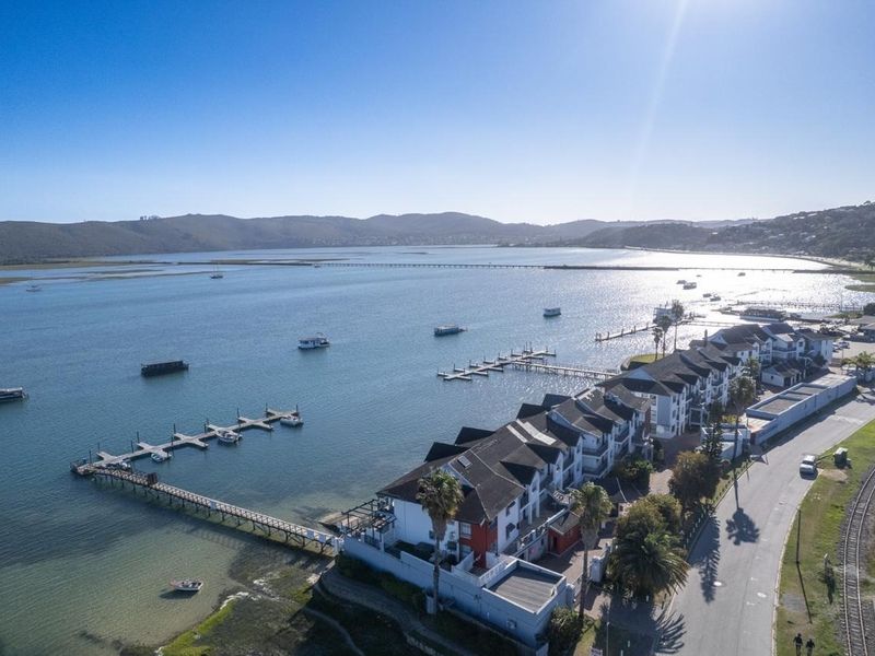 Aerial view of a waterfront apartment complex featuring private jetties, direct lagoon access, and proximity to local road and rail infrastructure.