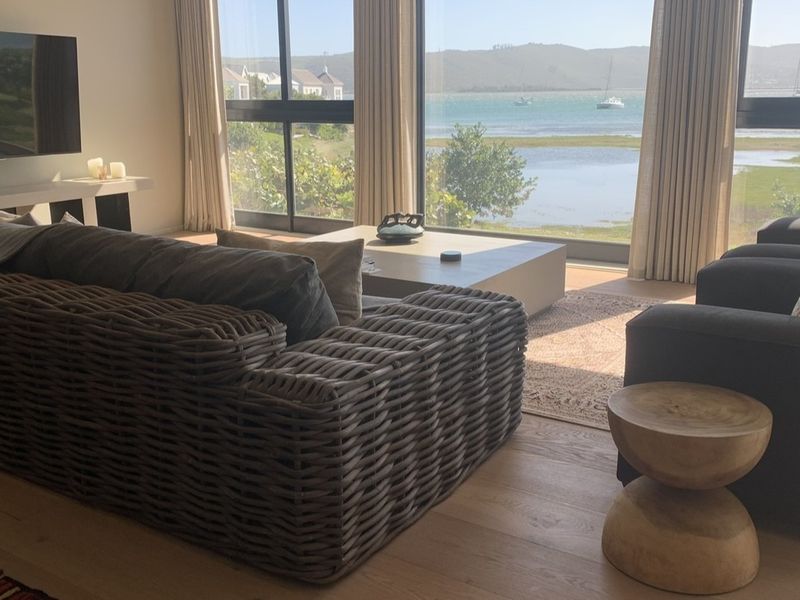 A bright, modern living room featuring expansive floor-to-ceiling windows that offer stunning waterfront views and abundant natural light.