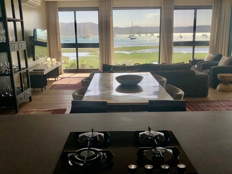 Spacious open-plan living and dining area featuring a modern gas cooktop, large windows, and stunning waterfront views.