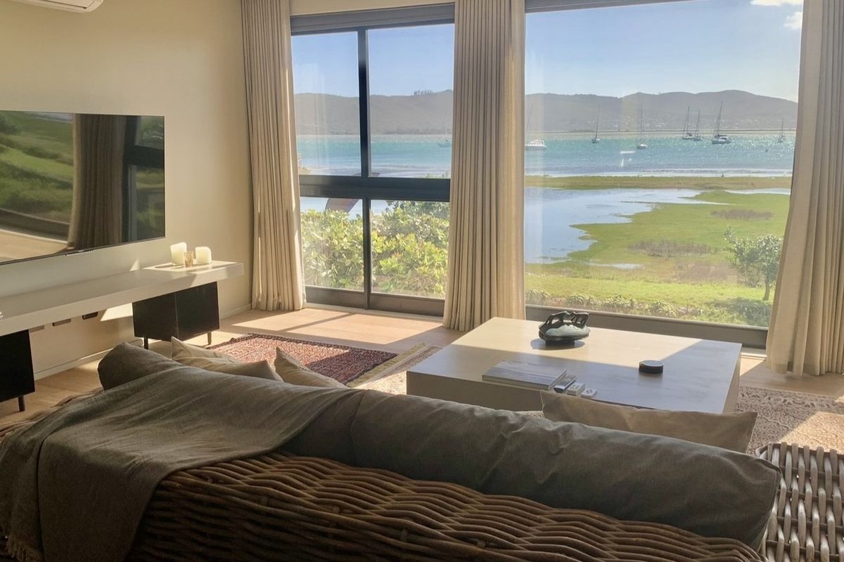 Bright and modern living room featuring expansive floor-to-ceiling windows with stunning panoramic water and landscape views.