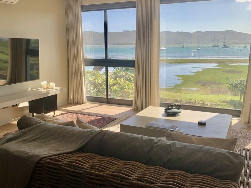 Bright and modern living room featuring expansive floor-to-ceiling windows with stunning panoramic water and landscape views.