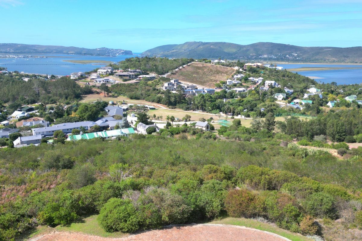 An elevated aerial view showcasing the surrounding residential estate, natural coastal landscape, and scenic water views.