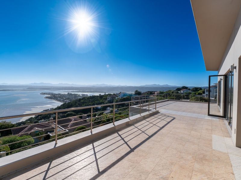 Spacious elevated balcony featuring tiled flooring and a stainless steel balustrade, offering expansive panoramic views of the lagoon and surrounding landscape.