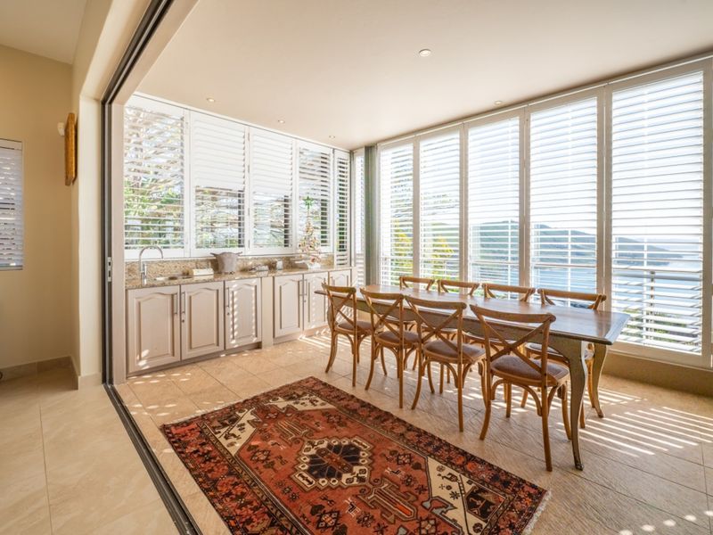 Bright open-plan dining area featuring tiled floors, built-in cabinetry with granite countertops, and expansive sliding glass doors with plantation shutters offering scenic views.