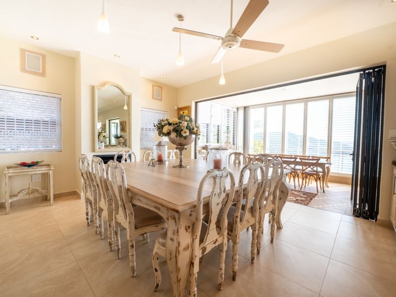 Spacious open-plan dining area featuring tiled floors, recessed lighting, a ceiling fan, and large bi-fold doors opening to an outdoor patio.