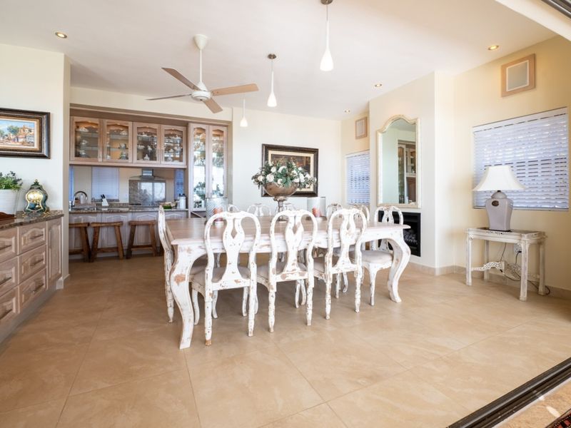 Spacious open-plan dining and kitchen area featuring tiled floors, built-in cabinetry, granite countertops, and a fireplace, with seamless access to outdoor space.