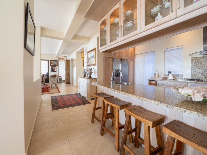 An open-plan kitchen featuring granite countertops, ample built-in cabinetry, and a breakfast bar, seamlessly flowing into the adjacent living area.