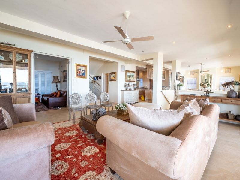 Spacious open-plan living area featuring tiled floors, recessed lighting, a ceiling fan, and integrated cabinetry, flowing into a kitchen and secondary living space.