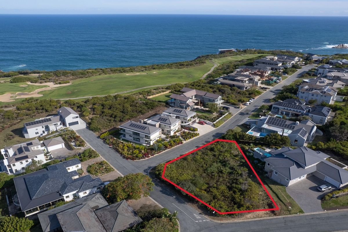 Aerial view of a prime vacant residential plot situated in a coastal estate, offering proximity to the ocean and established neighborhood infrastructure.
