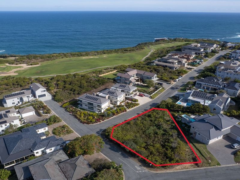 Aerial view of a prime vacant residential plot situated in a coastal estate, offering proximity to the ocean and established neighborhood infrastructure.