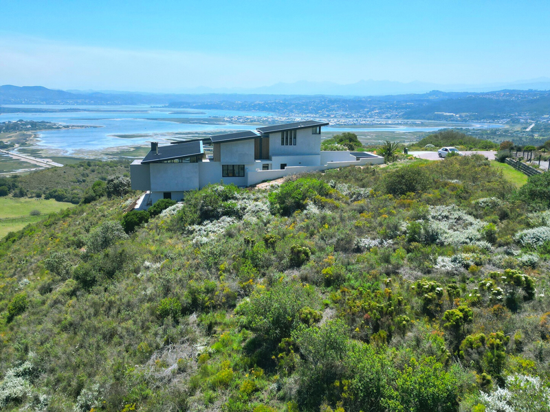 Aerial view of a modern residential property situated on a hillside, showcasing expansive landscape and estuary views.