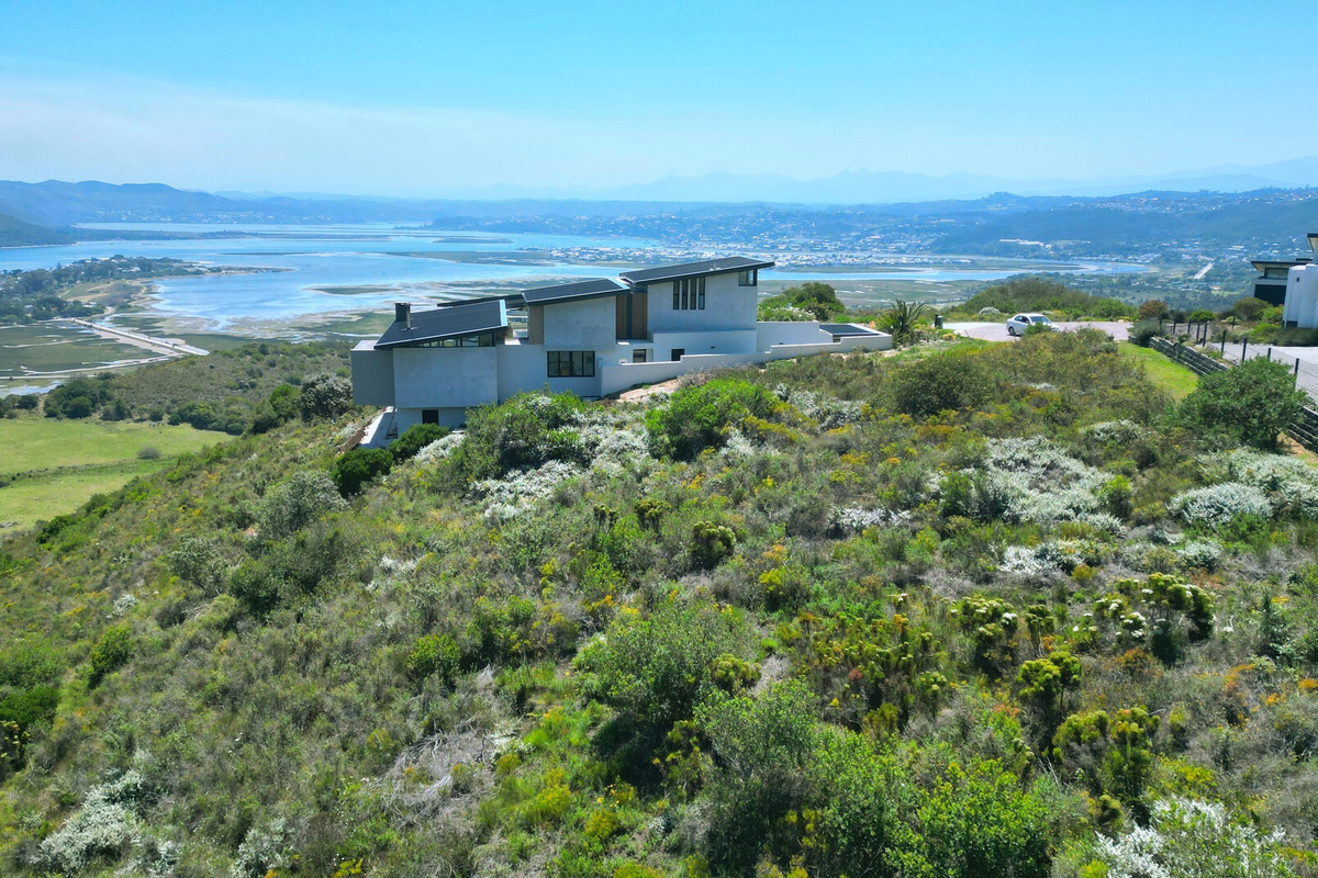 Aerial view of a modern residential property situated on a hillside, showcasing expansive landscape and estuary views.