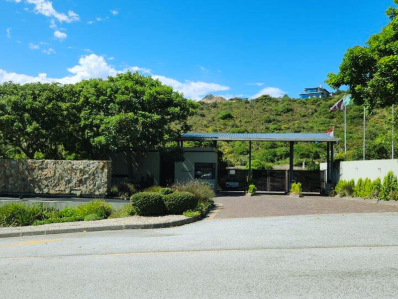 The entrance to Fernwood estate featuring a stone-clad monument, secure gated access, and well-maintained landscaped surroundings.