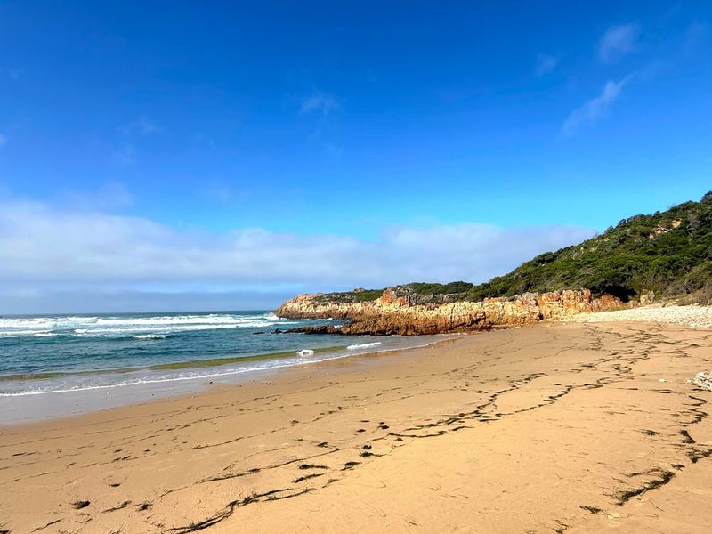 A scenic view of a sandy beach and rocky coastline, showcasing the natural landscape and coastal environment of the property.