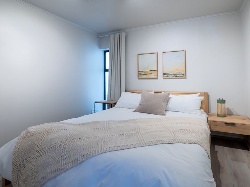 A well-maintained bedroom featuring neutral tones, laminate flooring, and a built-in wardrobe, offering a clean and comfortable living space.