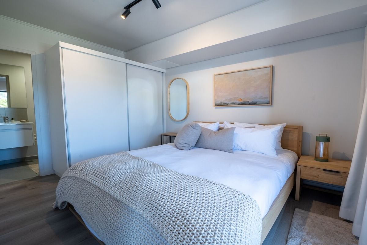 A well-maintained bedroom featuring modern track lighting, laminate flooring, and a built-in wardrobe, with convenient access to an adjoining en-suite bathroom.