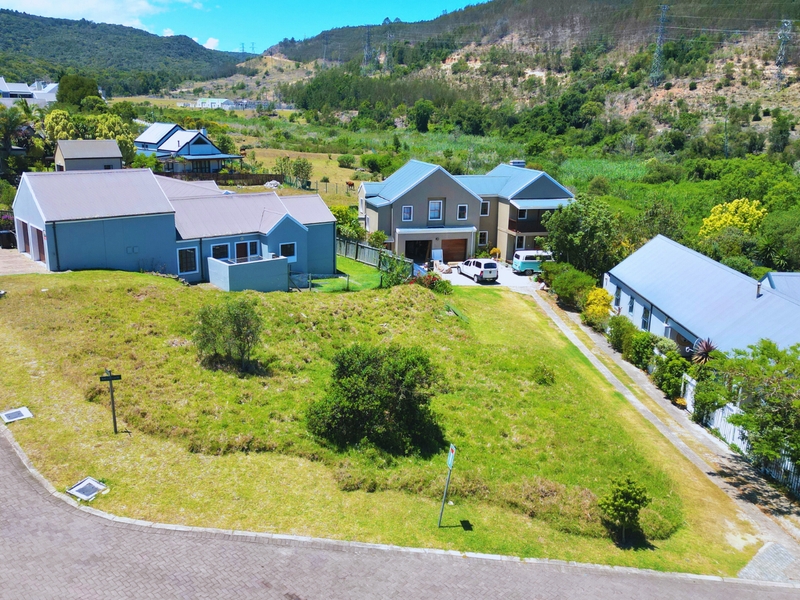 An aerial view of a vacant residential plot situated within an established neighborhood, featuring street access and surrounding residential properties.
