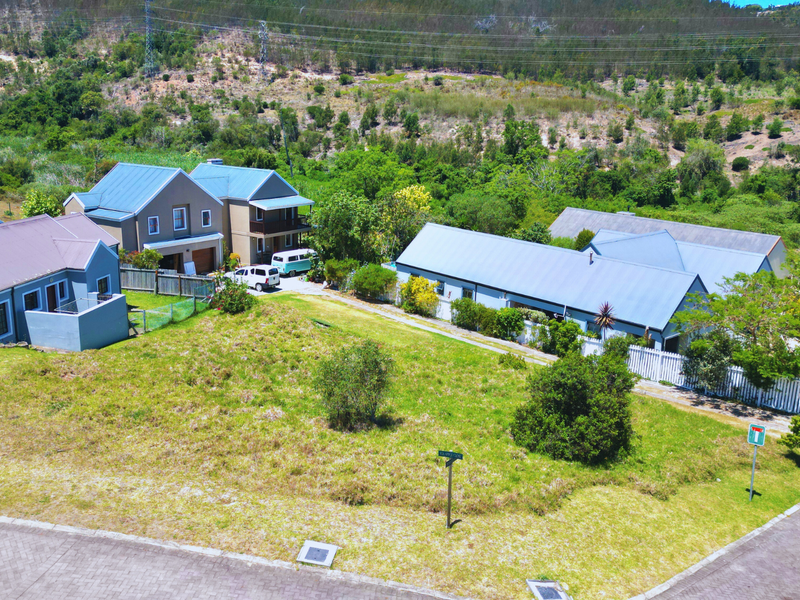 Aerial view of a residential vacant land plot situated in a suburban estate, surrounded by established homes and natural greenery.