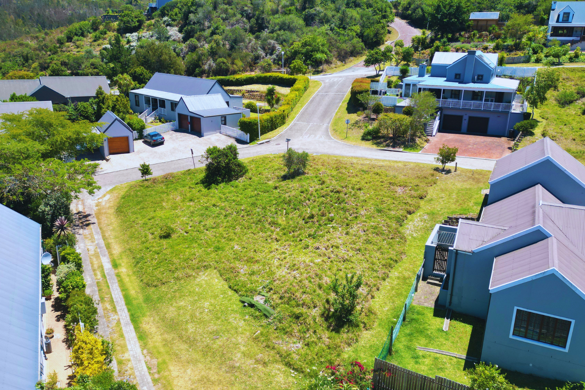 Aerial view of a vacant residential plot situated within a developed estate, featuring surrounding homes and established access roads.