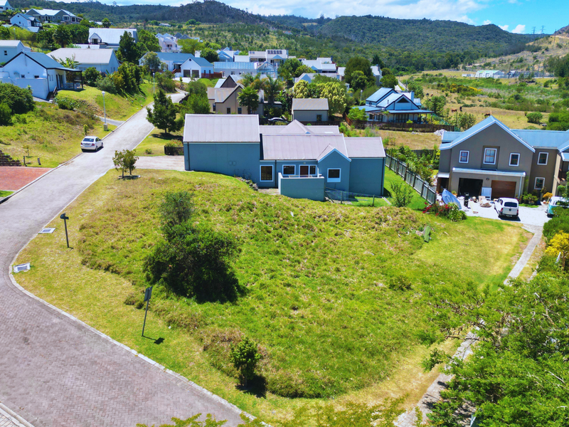 An aerial view of a vacant residential plot situated within a developed estate, featuring established road access and surrounding residential properties.
