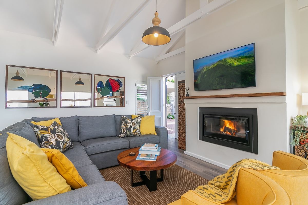 Cozy living room featuring a vaulted ceiling with exposed rafters, a modern built-in fireplace with a timber mantelpiece, and durable laminate flooring.