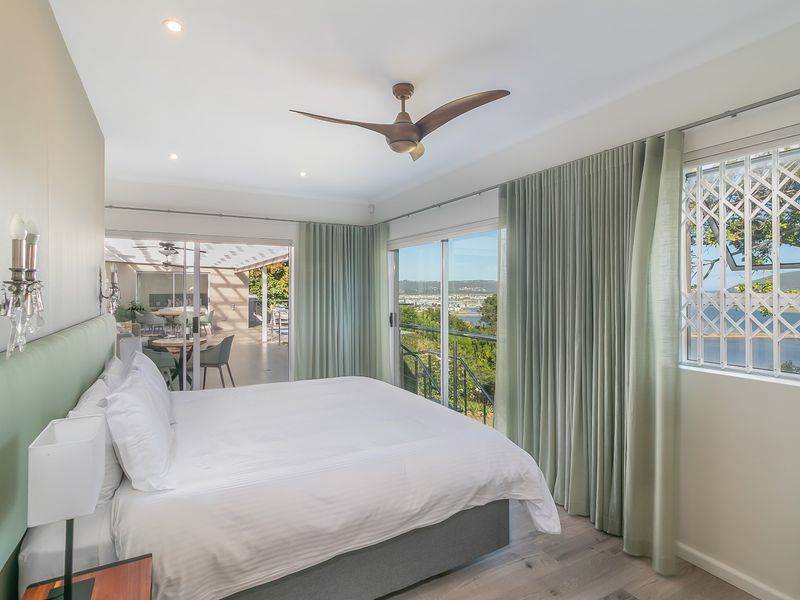 Spacious bedroom featuring laminate flooring, recessed lighting, a ceiling fan, and sliding glass doors opening onto a balcony with scenic views.