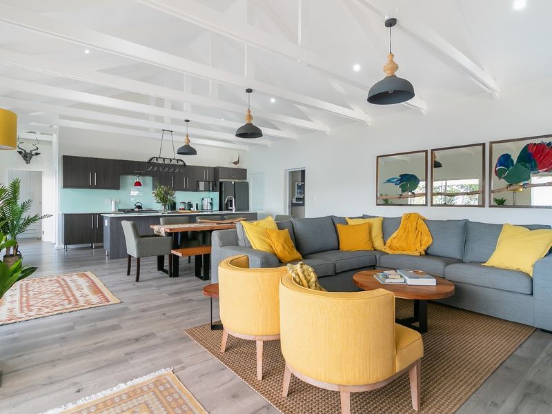 Spacious open-plan living and kitchen area featuring high vaulted ceilings with exposed rafters, modern cabinetry, and durable laminate flooring throughout.