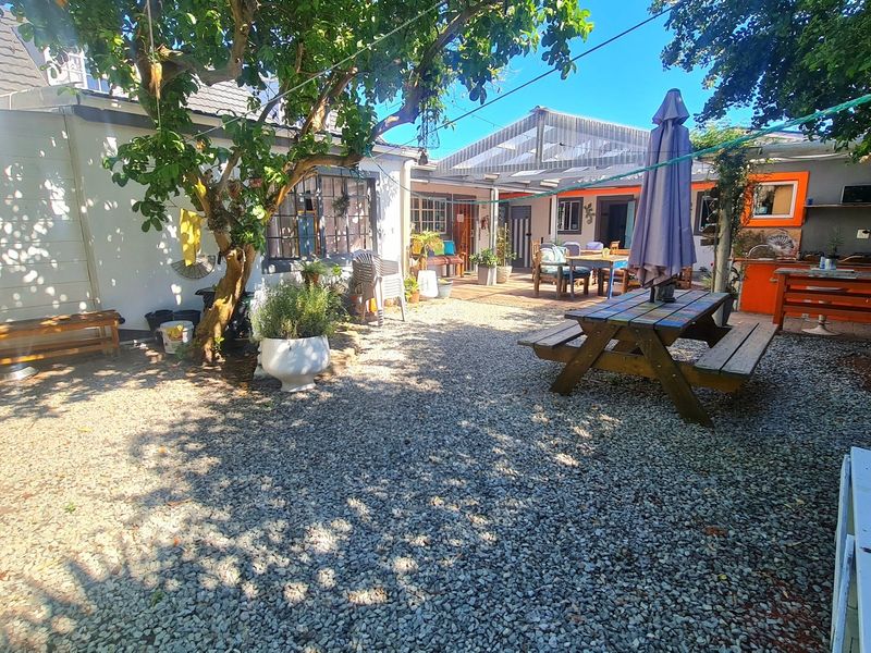 A spacious rear courtyard featuring a gravel surface, covered patio area, and an outdoor kitchen setup, ideal for relaxed lodge-style entertaining.