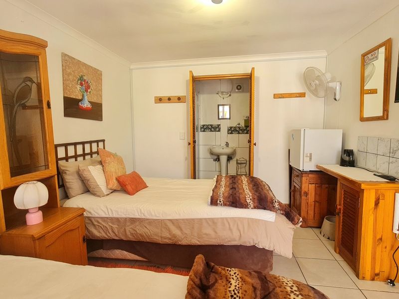 A lodge bedroom featuring tiled flooring, built-in cabinetry, and direct access to an en-suite bathroom with a pedestal basin.