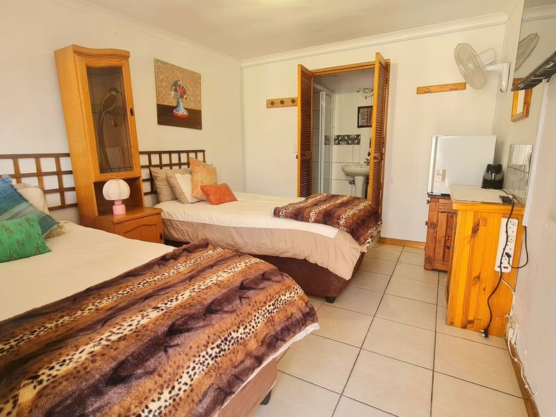 A functional bedroom featuring tiled flooring, a wall-mounted fan, and direct access to an en-suite bathroom.