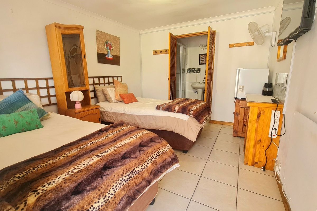 A functional bedroom featuring tiled flooring, a wall-mounted fan, and direct access to an en-suite bathroom.
