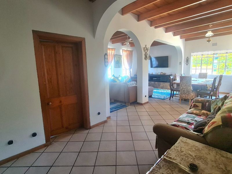 Spacious open-plan living and dining area featuring exposed timber ceiling beams, arched architectural details, and ceramic tiled flooring.
