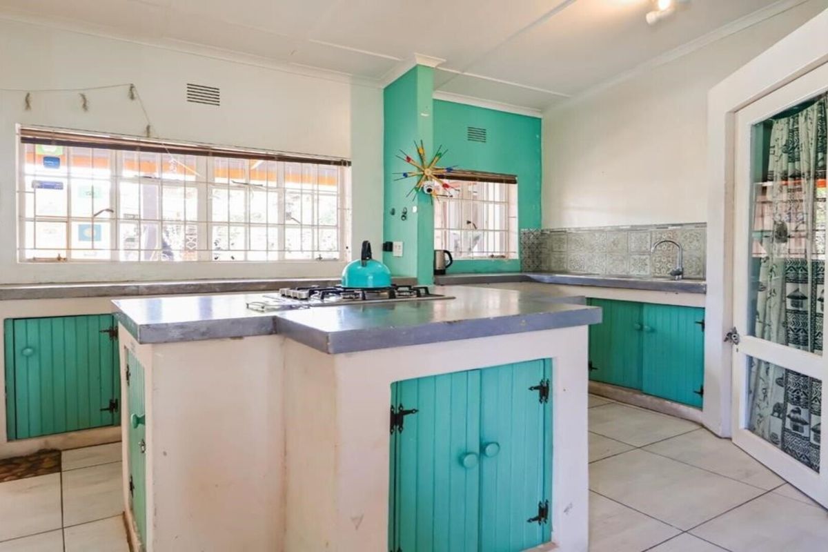 A functional kitchen featuring built-in cabinetry, concrete countertops, a gas hob, and tiled finishes, offering a rustic aesthetic with potential for modernization.