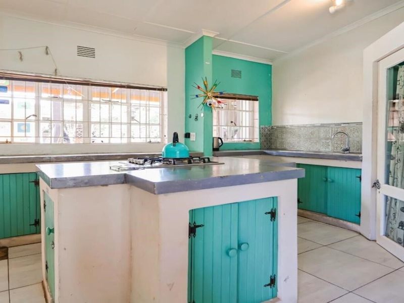 A functional kitchen featuring built-in cabinetry, concrete countertops, a gas hob, and tiled finishes, offering a rustic aesthetic with potential for modernization.