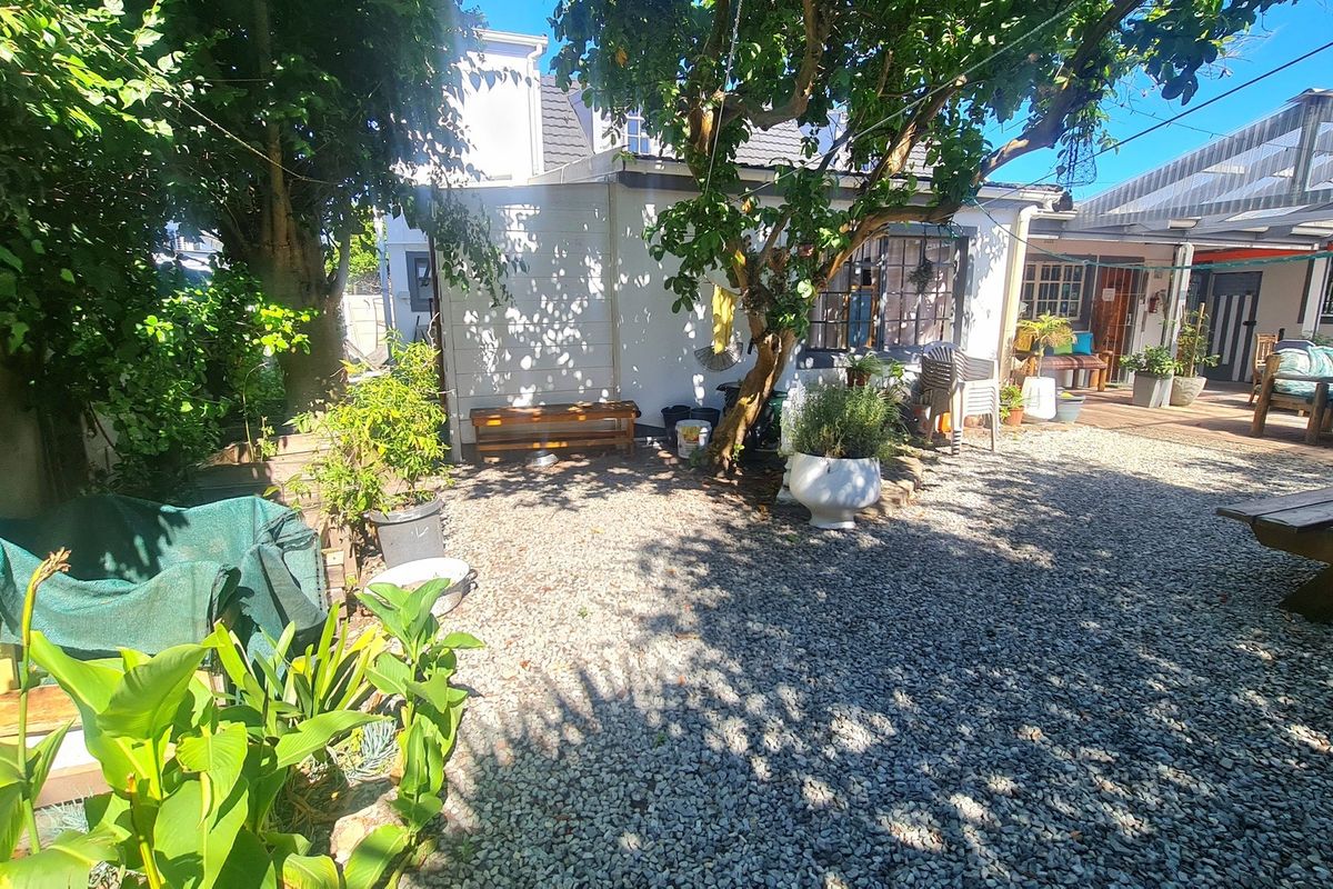 A rear courtyard area featuring a gravel surface, mature trees, and a covered patio space attached to the main lodge building.