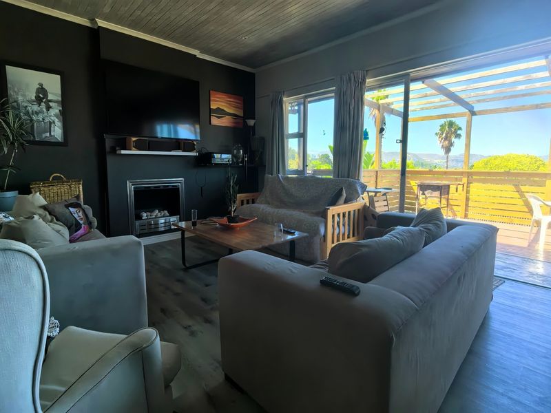 A cozy living room featuring a built-in fireplace, timber ceiling, and large sliding doors that open onto an outdoor deck area.