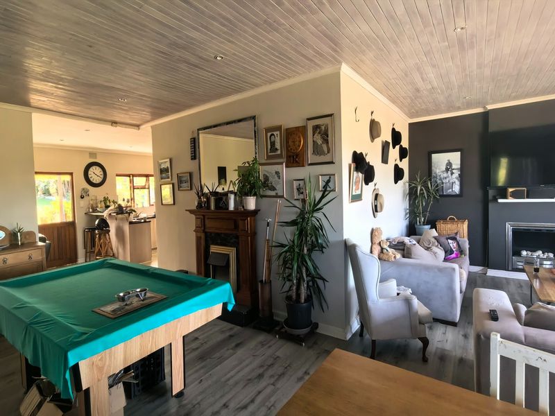 Spacious open-plan living area featuring a timber-clad ceiling, laminate flooring, and a central fireplace with a wooden mantelpiece.