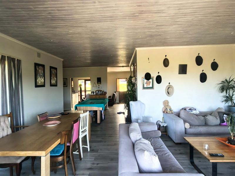 Spacious open-plan living and dining area featuring timber-look ceilings, laminate flooring, and large sliding doors providing access to the outdoors.