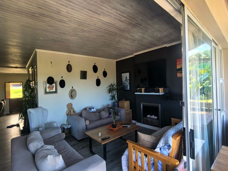Spacious living room featuring a fireplace, timber-clad ceiling, and large sliding glass doors that provide seamless access to the outdoor area.