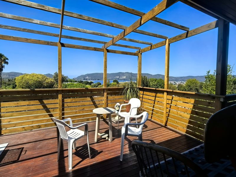 A spacious elevated timber deck featuring a pergola structure and panoramic views of the surrounding landscape and water.