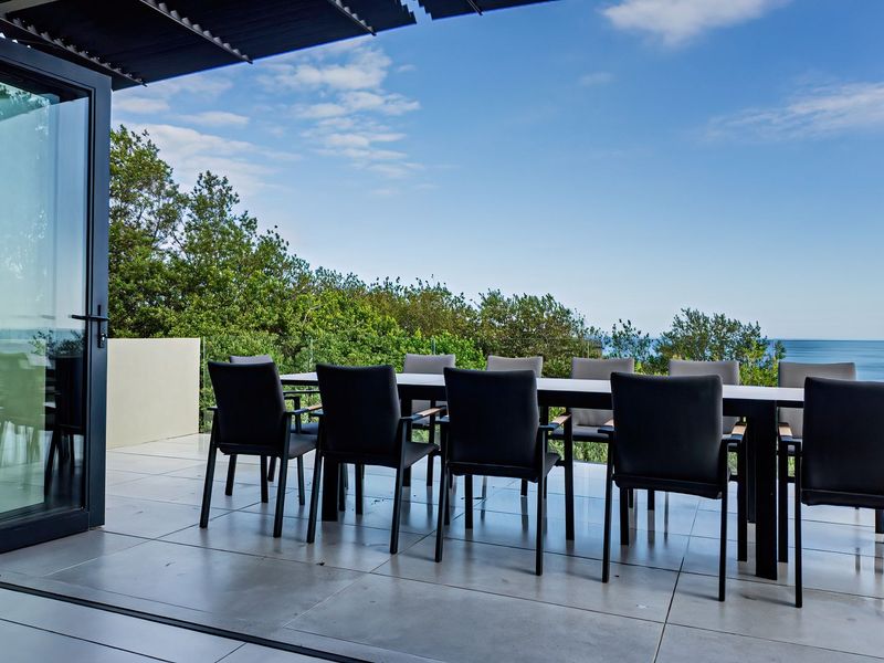 Spacious covered balcony featuring large format floor tiles, glass balustrades, and seamless bi-fold door access, offering expansive ocean views.