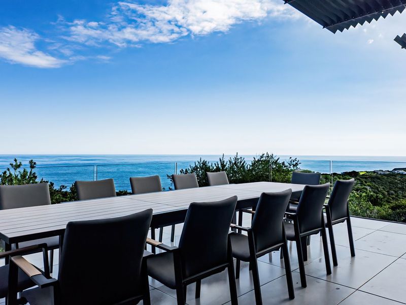 Spacious covered balcony featuring modern tiled flooring and a glass balustrade, offering expansive, unobstructed ocean views.